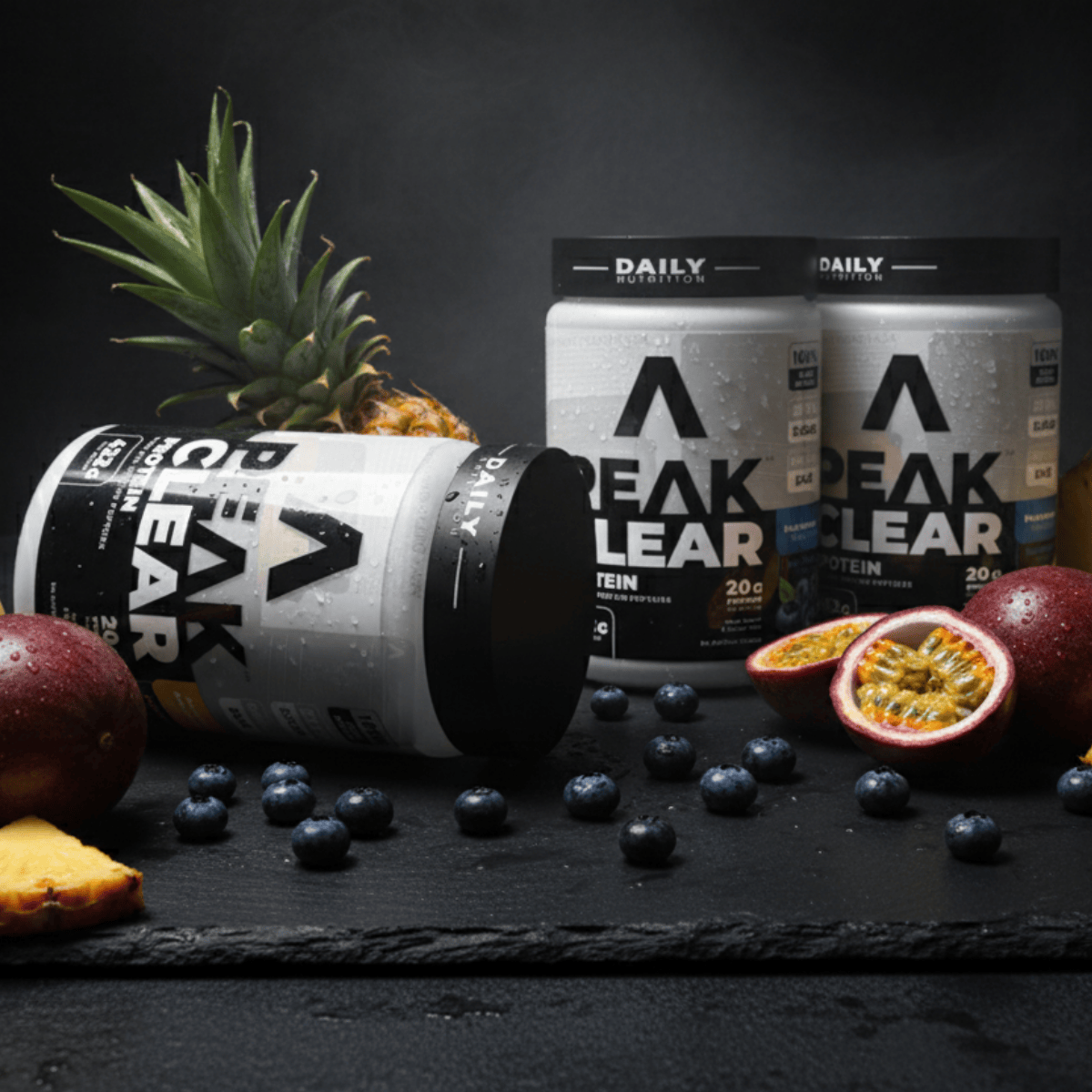 Peak Clear supplement containers with fruits on a dark surface