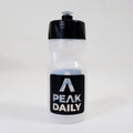 Clear water bottle with black cap and Peak Daily label on a white background