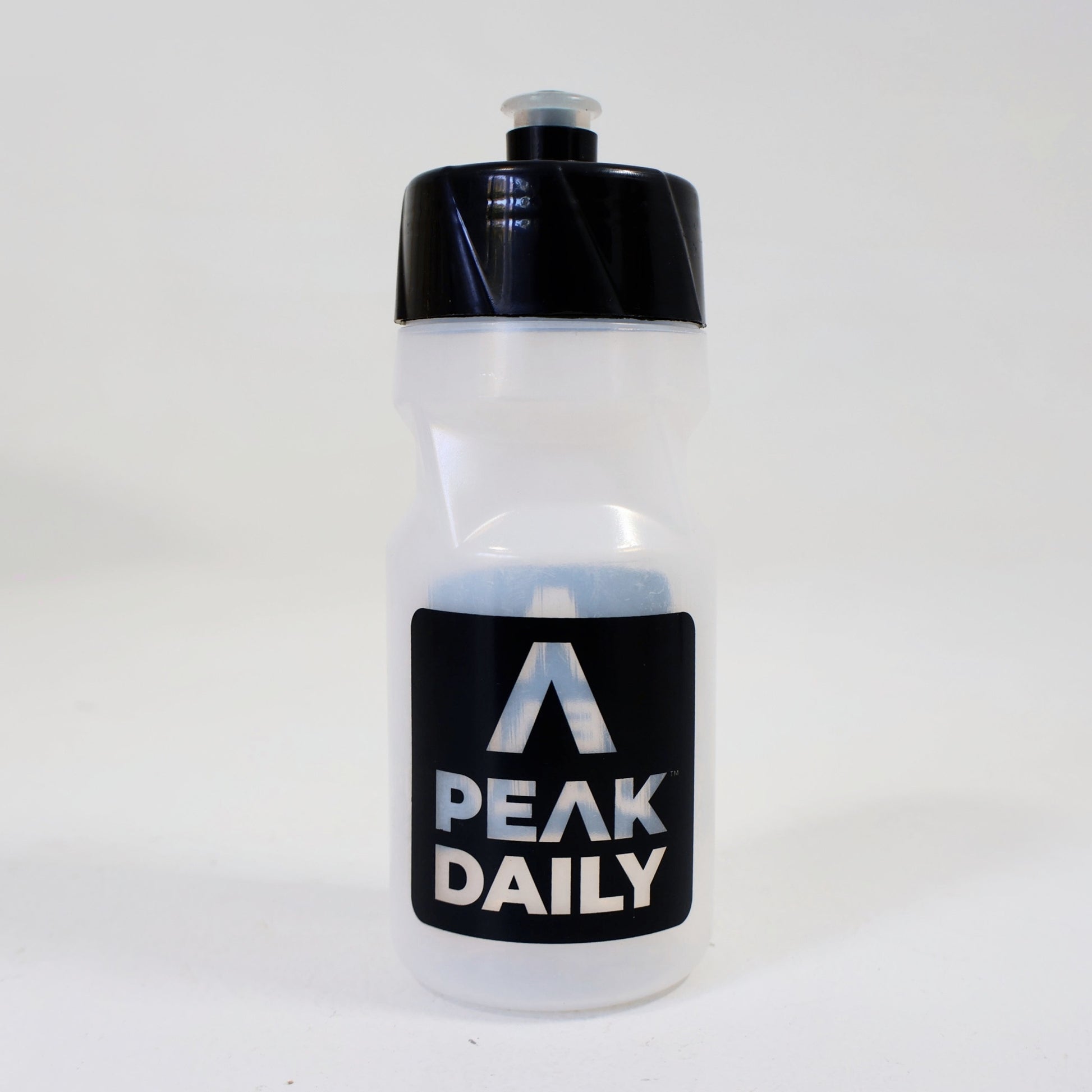Clear water bottle with black cap and Peak Daily label on a white background