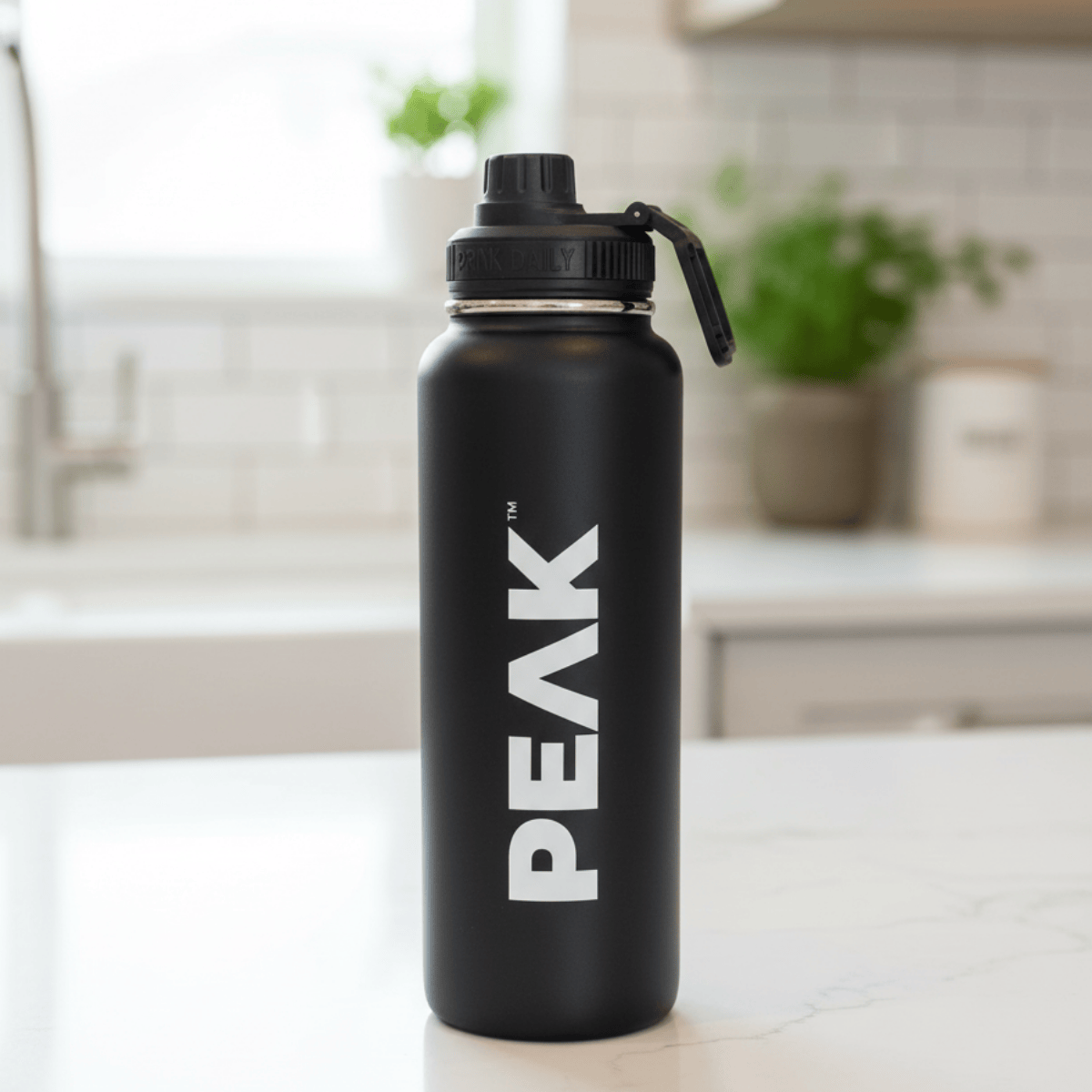 Black water bottle with 'PEAK' logo on a kitchen counter